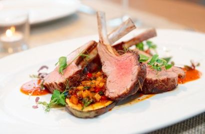 A white plate topped with meat and vegetables on a table.